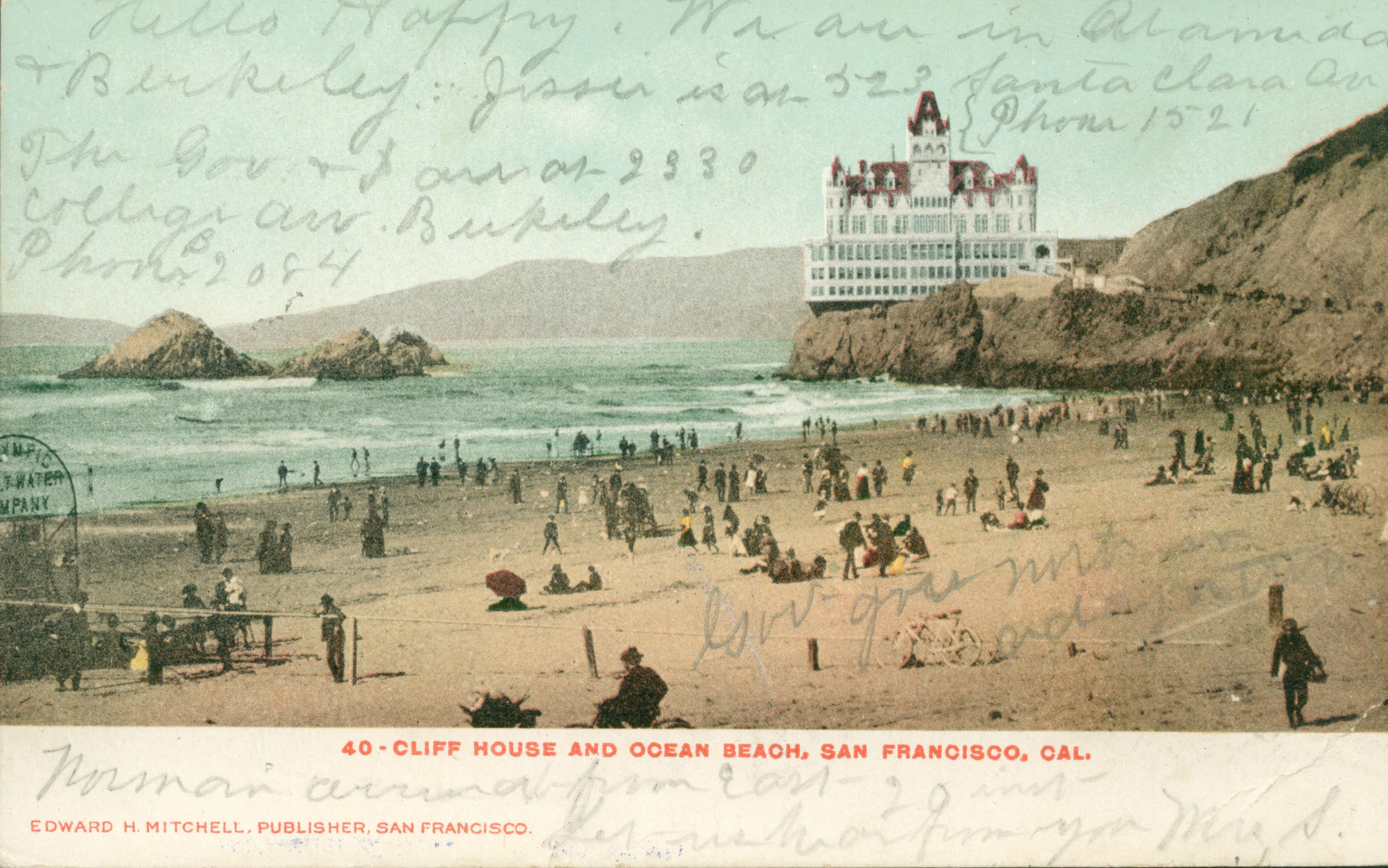 Shows the Cliff House and Seal Rocks with onlookers on the beach